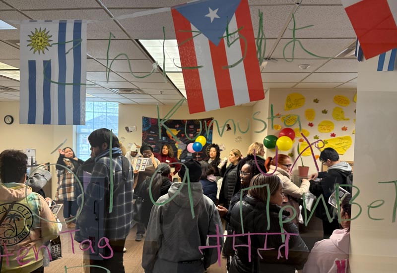 A vibrant gathering with people celebrating cultural diversity, featuring flags of Uruguay and Puerto Rico and colorful decorations.